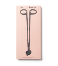 product shot of exterior pink box with black text, boy smells logo in black and black image of wick trimmer against a neutral background.